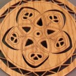 A wooden circular design with a peace symbol in the center.