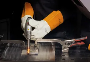 A person wearing white gloves and orange gloves is welding.