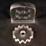 A clear plastic gear with a hole in it.