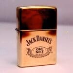 A gold lighter with jack daniels on it.